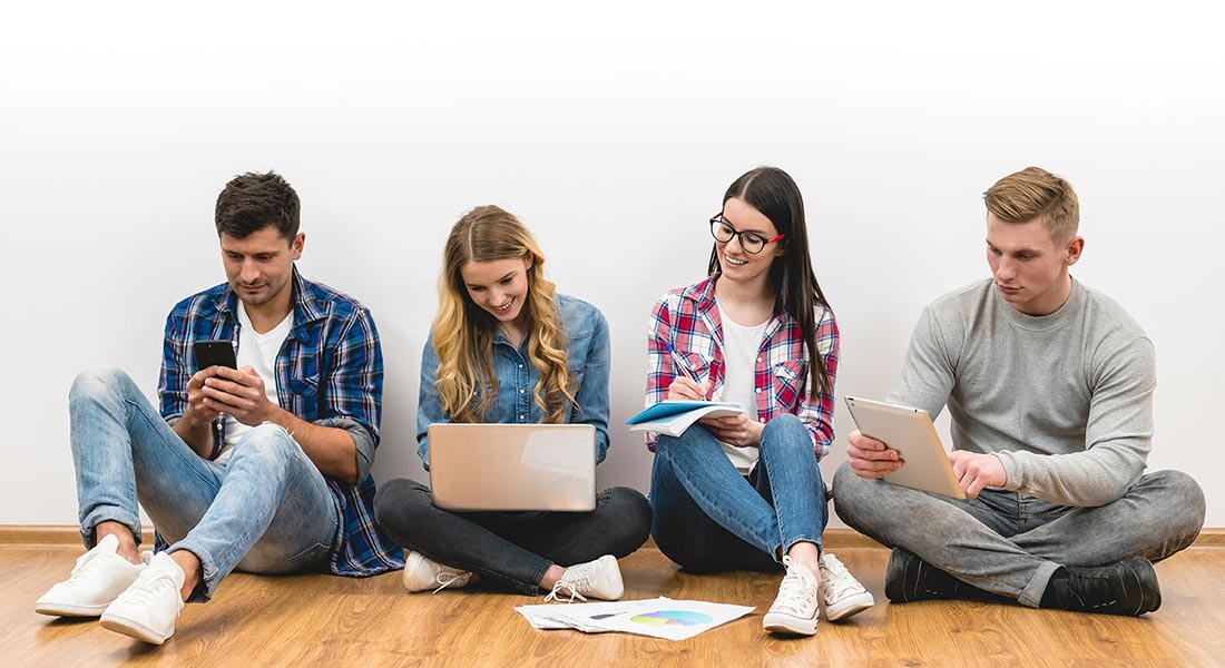 Grupo de jóvenes trabajando con dispositivos y computadoras descontracturadamente